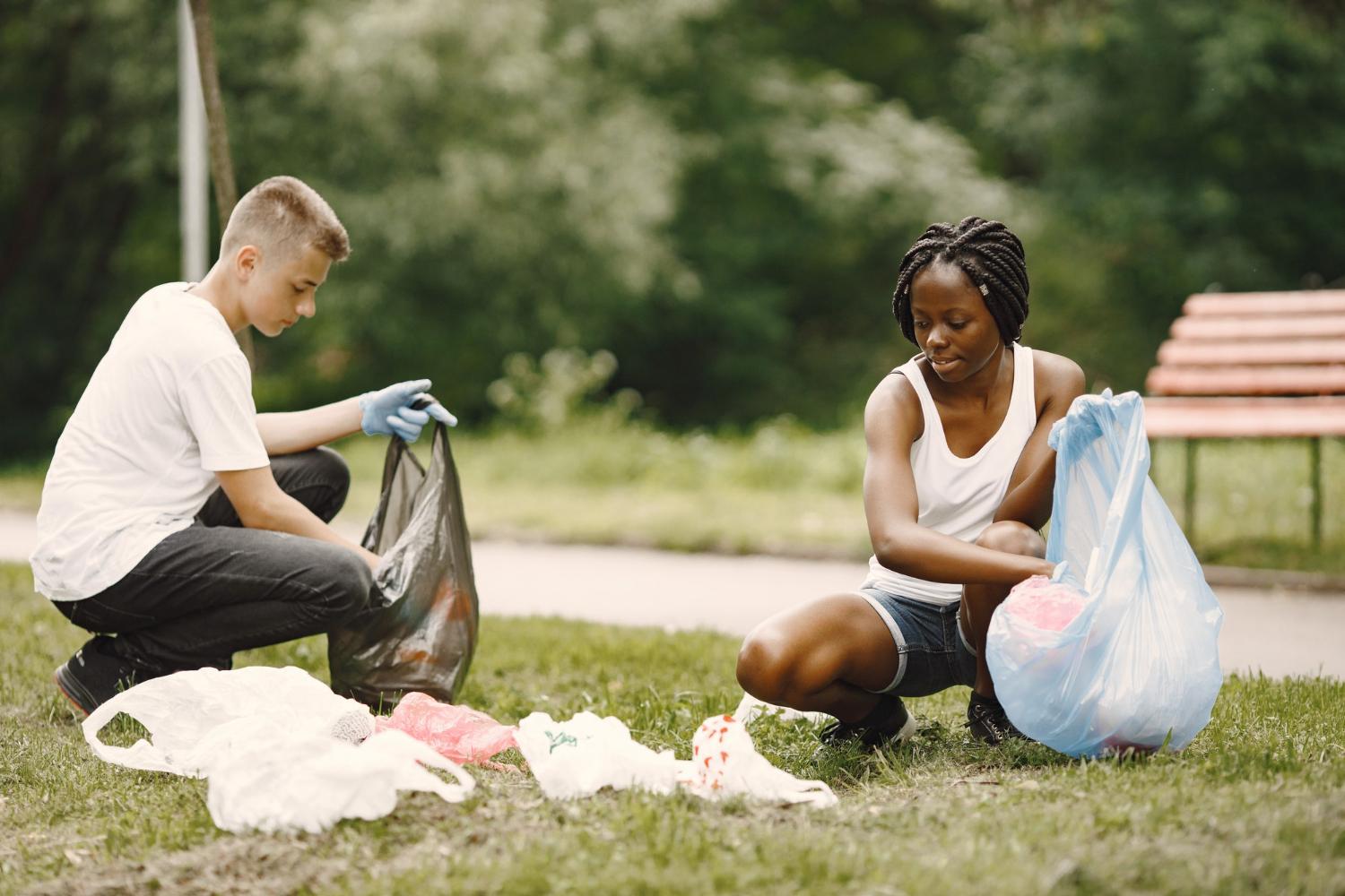 A boy and a girl picking up cans in a park